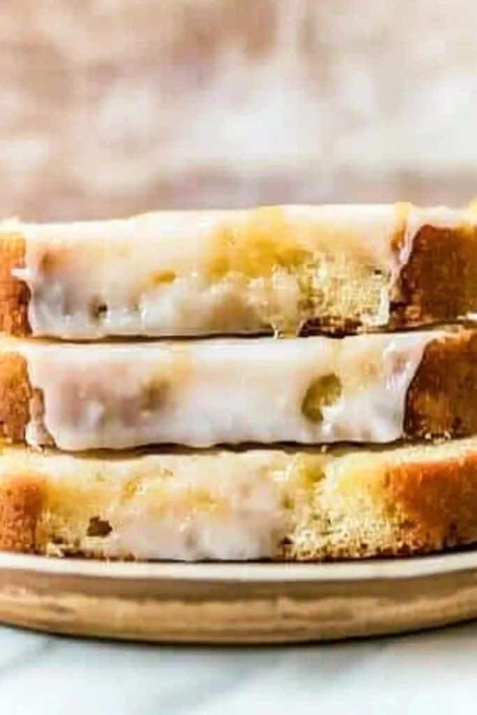 Ein frisch gebackener Zitronenkuchen mit Zuckerguss, der über die Seiten tropft. Der Kuchen hat eine goldbraune Kruste und eine weiche, luftige Textur.